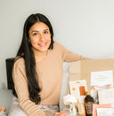 woman opening a self care box with wellness products and surprise gift items inside